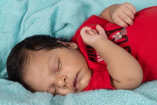 Infant asleep lying on his stomach, dressed in red clothes