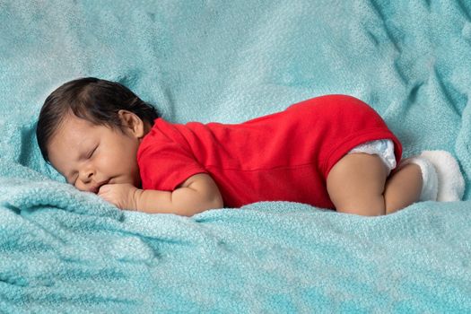 Baby sleeping on his stomach, dressed in red clothes