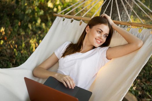 woman with laptop lies in hammock freelance travel. High quality photo