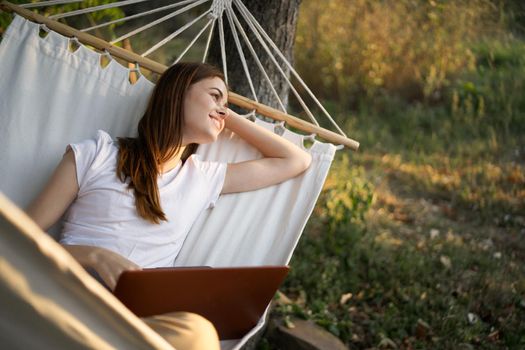 woman with laptop and lies in a hammock vacation nature freelance. High quality photo