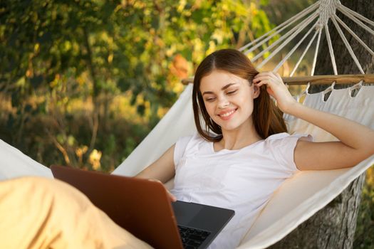 women outdoors lies in a hammock with a laptop freelance internet. High quality photo