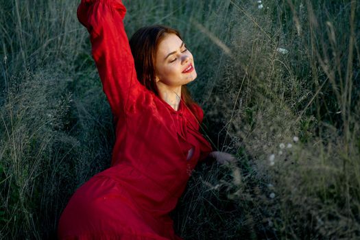 pretty woman in red dress lies on the grass nature sun. High quality photo