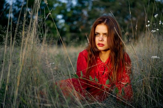 woman in a red dress lies on the grass in the field nature fashion. High quality photo