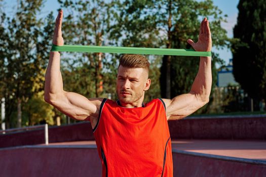 athletic man on the sports ground rubber band exercise. High quality photo