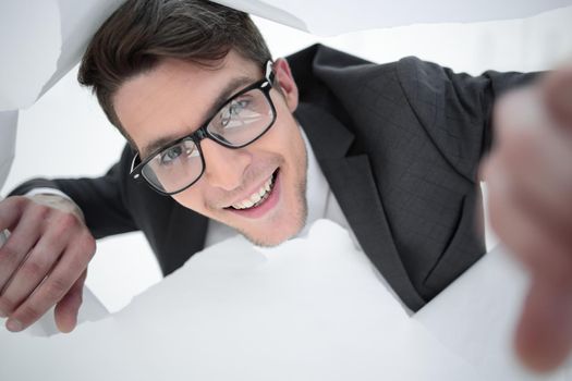 happy businessman with glasses looking through a hole in the paper.photo with copy space