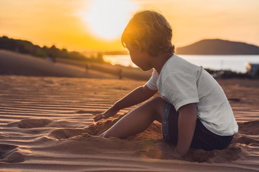 The boy in the red desert at dawn. Traveling with children concept.