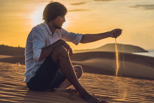 A man is pouring sand in the desert. Sand through the fingers of the concept.