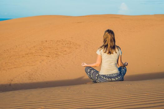 young woman meditating in rad sandy desert at sunset or dawn