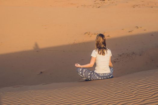 young woman meditating in rad sandy desert at sunset or dawn