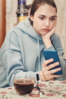 A beautiful brunette with long hair combed back looks into her smartphone. Vertical frame