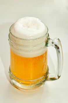 Clear glass with light beer and foam on top. Vertical shot
