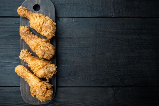 Crispy fried chicken drumstick on black wooden table, top view, with copy space.