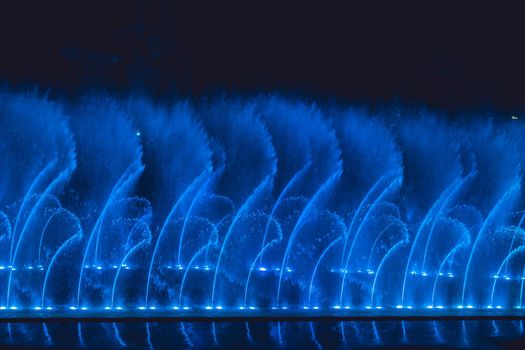 Multicolored dancing water jet fountain in the dark.
