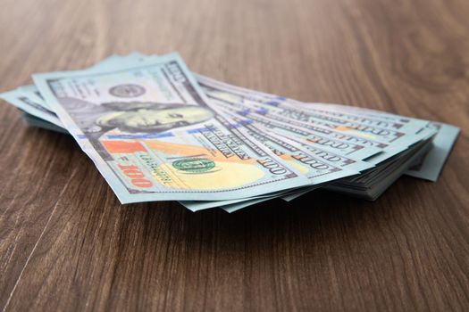 US Dollar bills stack on wooden table