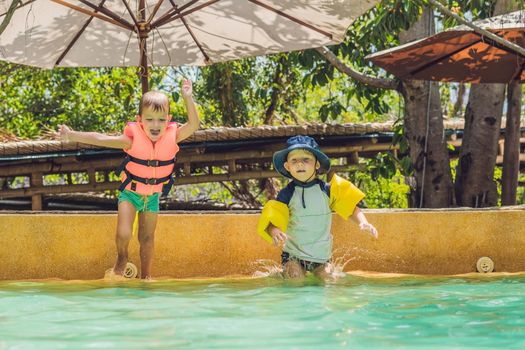 two young boys friends jumping in the pool.