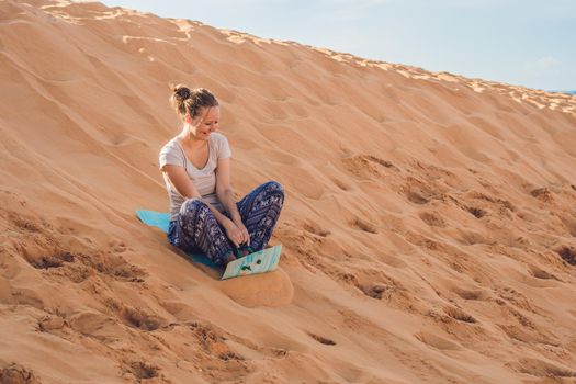 Young woman rolls on a toboggan in the sledge in the desert.