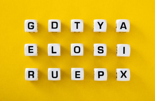 White cubes with letters scattered randomly on a yellow background