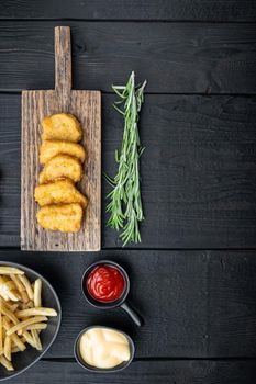 Fried crispy chicken nuggets meat on black wooden background, top view, with space for text.