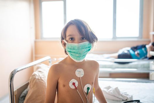 Little cute boy in hospital at bed indoors