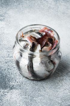 Pickled salted anchovies fillet set, in glass jar, on gray background