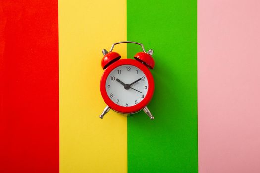 Colorful alarm clock on colorful background. (Flat lay)