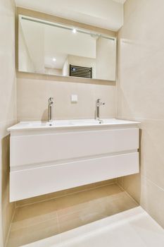 Expensive vessel sink made of natural stone with white faucet under mirror in bathroom