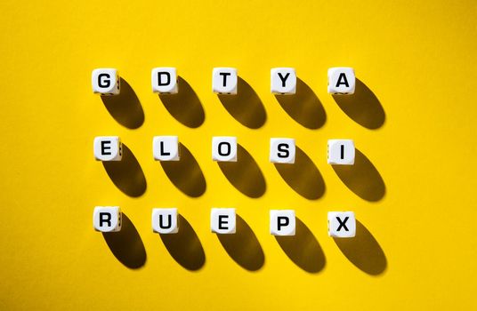 White cubes with letters scattered randomly on a yellow background