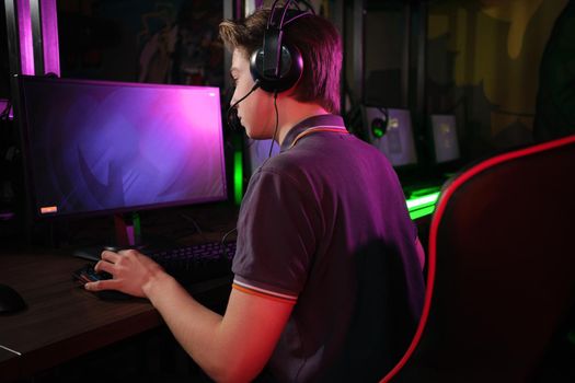 Professional photo of young male caucasian cyber sportsman in gaming club training for important match. Back view