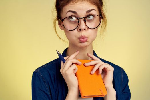 woman student with glasses notepad with pen yellow background. High quality photo