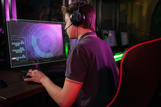 Professional photo of young male caucasian cyber sportsman in gaming club training for important match. Back view. laser screen, projector, augmented reality, AR, VR