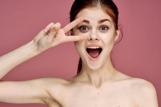 cheerful woman with bare shoulders posing clear skin pink background. High quality photo