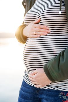 Pregnant woman hugs her belly. Close-up. High quality photo
