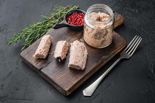 Canned tuna fillet meat in olive oil, on black background