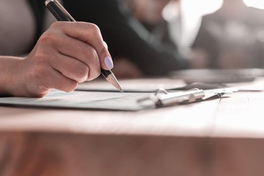 Hand of businesswoman writing on paper in office