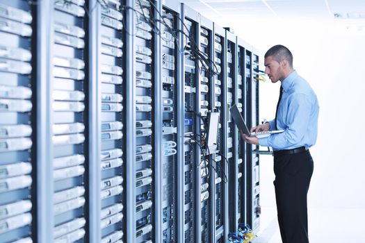 young engeneer business man with thin modern aluminium laptop in network server room