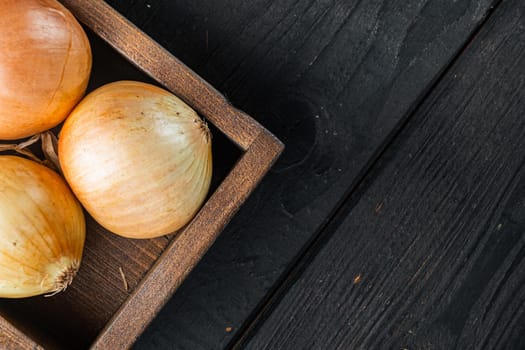 Fresh onions, on black wooden table background, top view flat lay with copy space for text