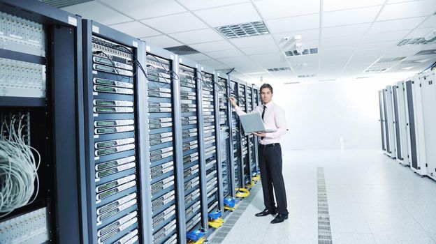 young engeneer business man with thin modern aluminium laptop in network server room