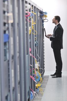 young engeneer business man with thin modern aluminium laptop in network server room