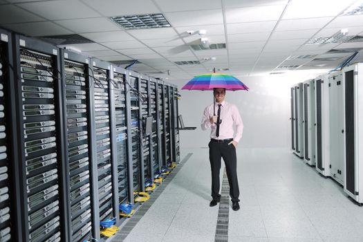 young handsome business man  engineer in 
businessman hold  rainbow colored umbrella in server datacenter room  and representing security and antivirus sofware protection concept