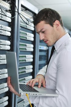 young engeneer business man with thin modern aluminium laptop in network server room