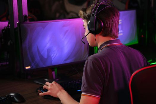 Professional photo of young male caucasian cyber sportsman in gaming club training for important match. Back view