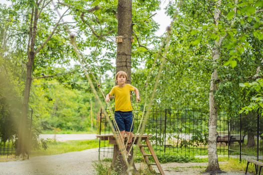 Little boy in a rope park. Active physical recreation of the child in the fresh air in the park. Training for children.