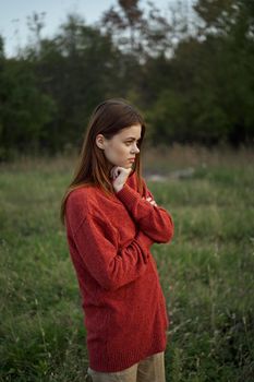 woman in a red sweater outdoors in a field walk. High quality photo