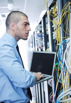 young engeneer business man with thin modern aluminium laptop in network server room