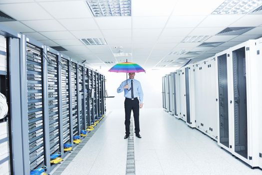 young handsome business man  engineer in 
businessman hold  rainbow colored umbrella in server datacenter room  and representing security and antivirus sofware protection concept