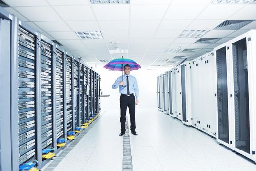 young handsome business man  engineer in 
businessman hold  rainbow colored umbrella in server datacenter room  and representing security and antivirus sofware protection concept