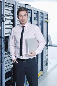 young engeneer business man with thin modern aluminium laptop in network server room