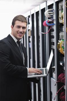 young engeneer business man with thin modern aluminium laptop in network server room