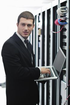 young engeneer business man with thin modern aluminium laptop in network server room