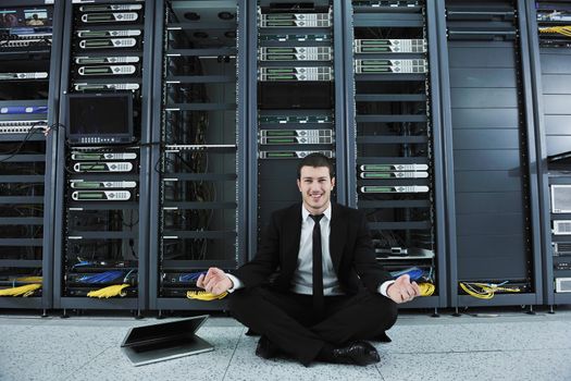 young handsome business man in black suit and tie practice yoga and relax at network server room while representing stres control concept